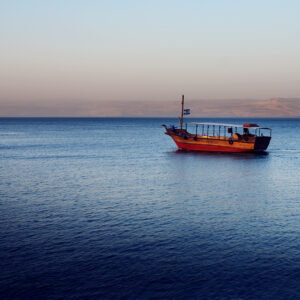 Boat in sunset, Sea of Galilee near Capernaum, Israel. Golan Heights can be seen in the background.